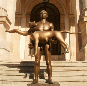 Sculptura recent inaugurată este un Traian, împăratul roman, gol-goluţ, ţinând în levitaţie în dreptul abdomenului o lupa capitolina victimă a mutaţiilor genetice.